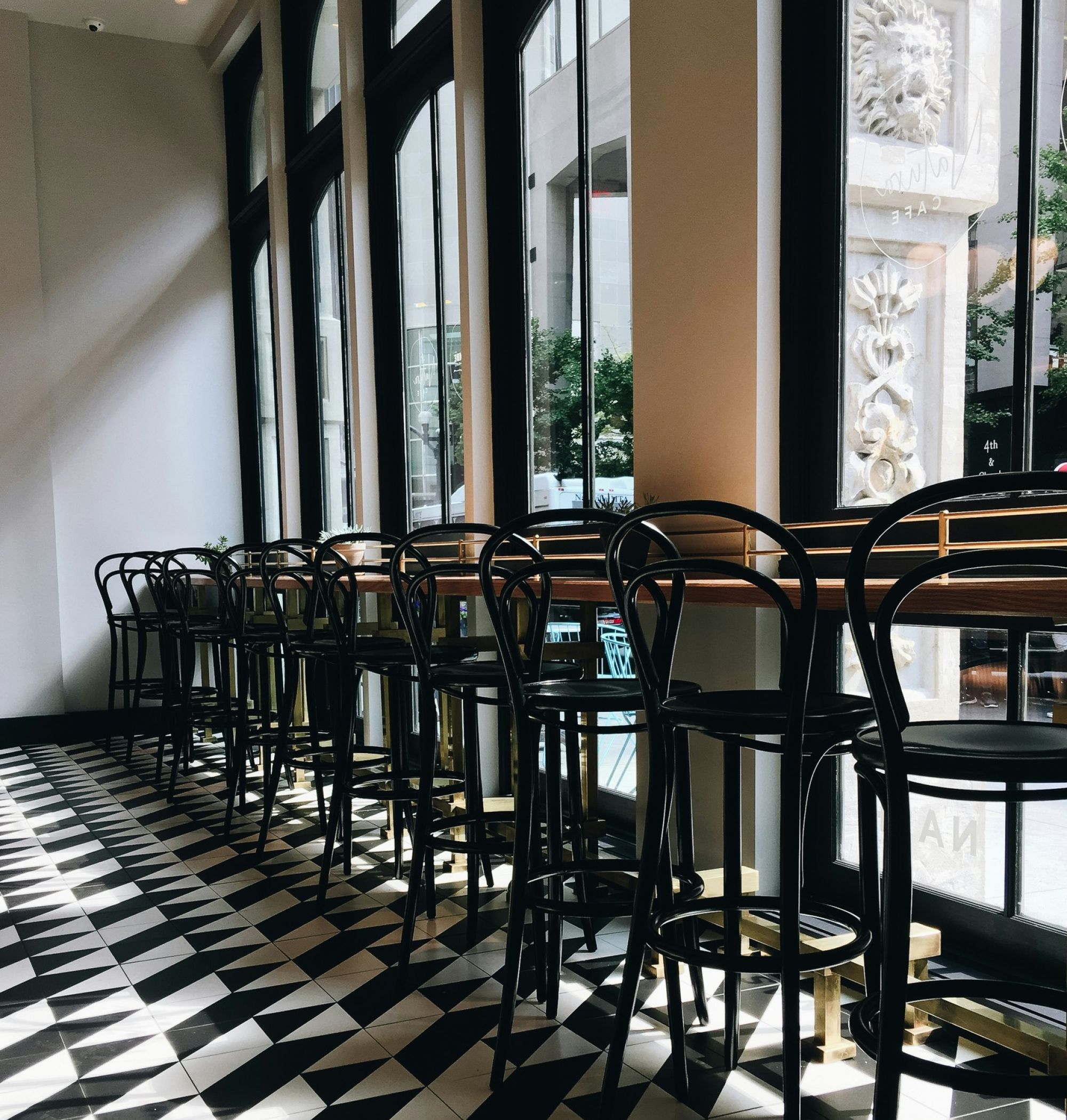 Black bar stools lined up at a window bar on a black checkered floor in downtown Nashville, TN