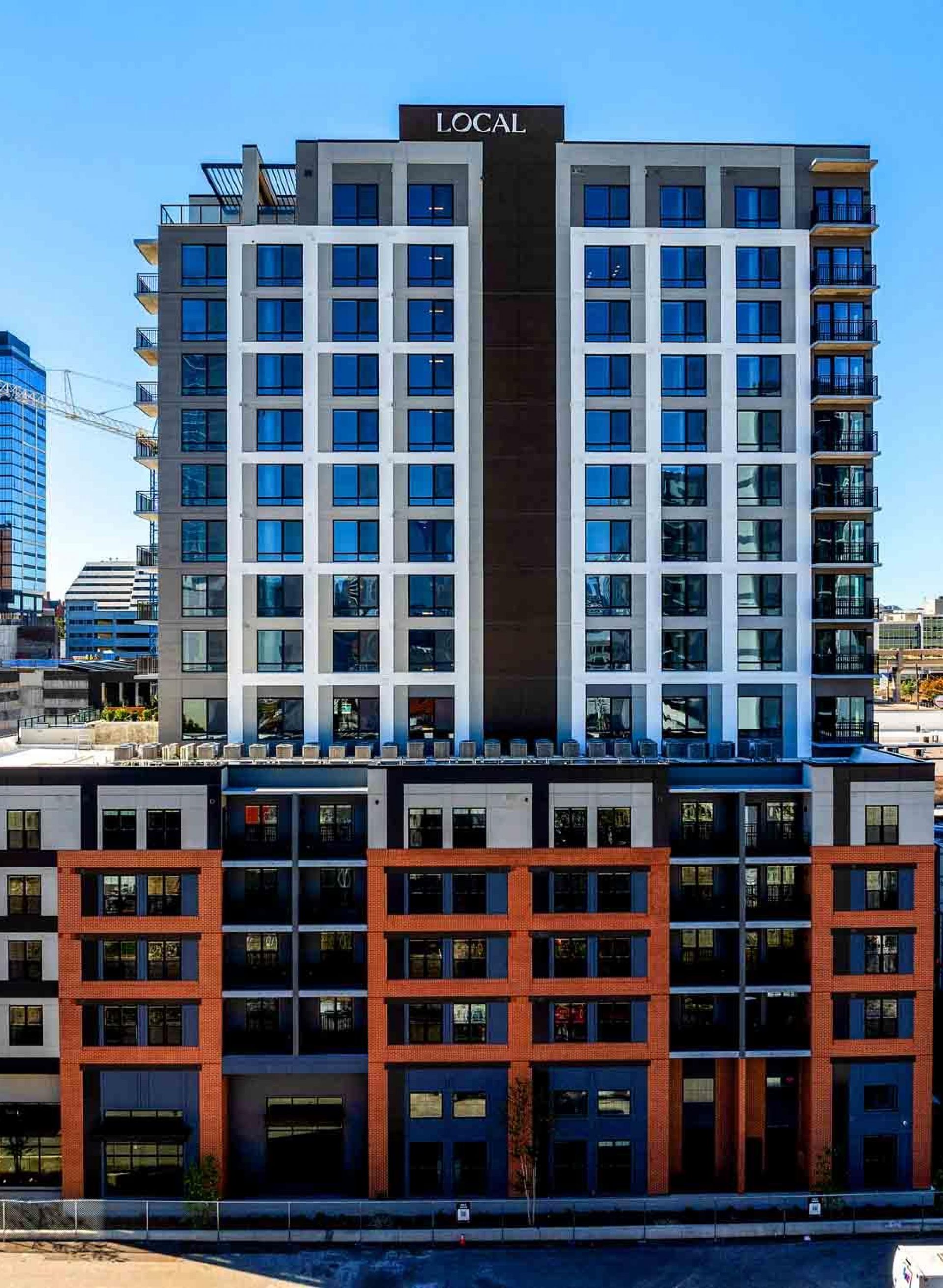 LOCAL Nashville modern multi-story apartment building with large windows, located in an urban cityscape on a sunny day.