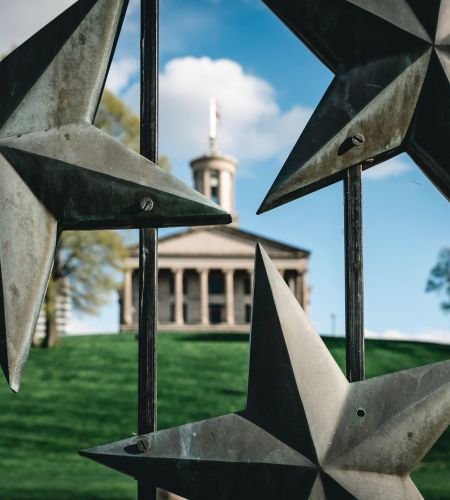 Tennessee State Capitol building on a hill behind a star-adorned metal gate in Nashville, Tennessee