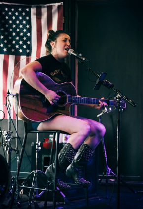 Singer playing guitar wearing cowboy boots in a bar in Nashville, TN