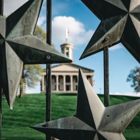 Tennessee State Capitol building on a hill behind a star-adorned metal gate in Nashville, Tennessee