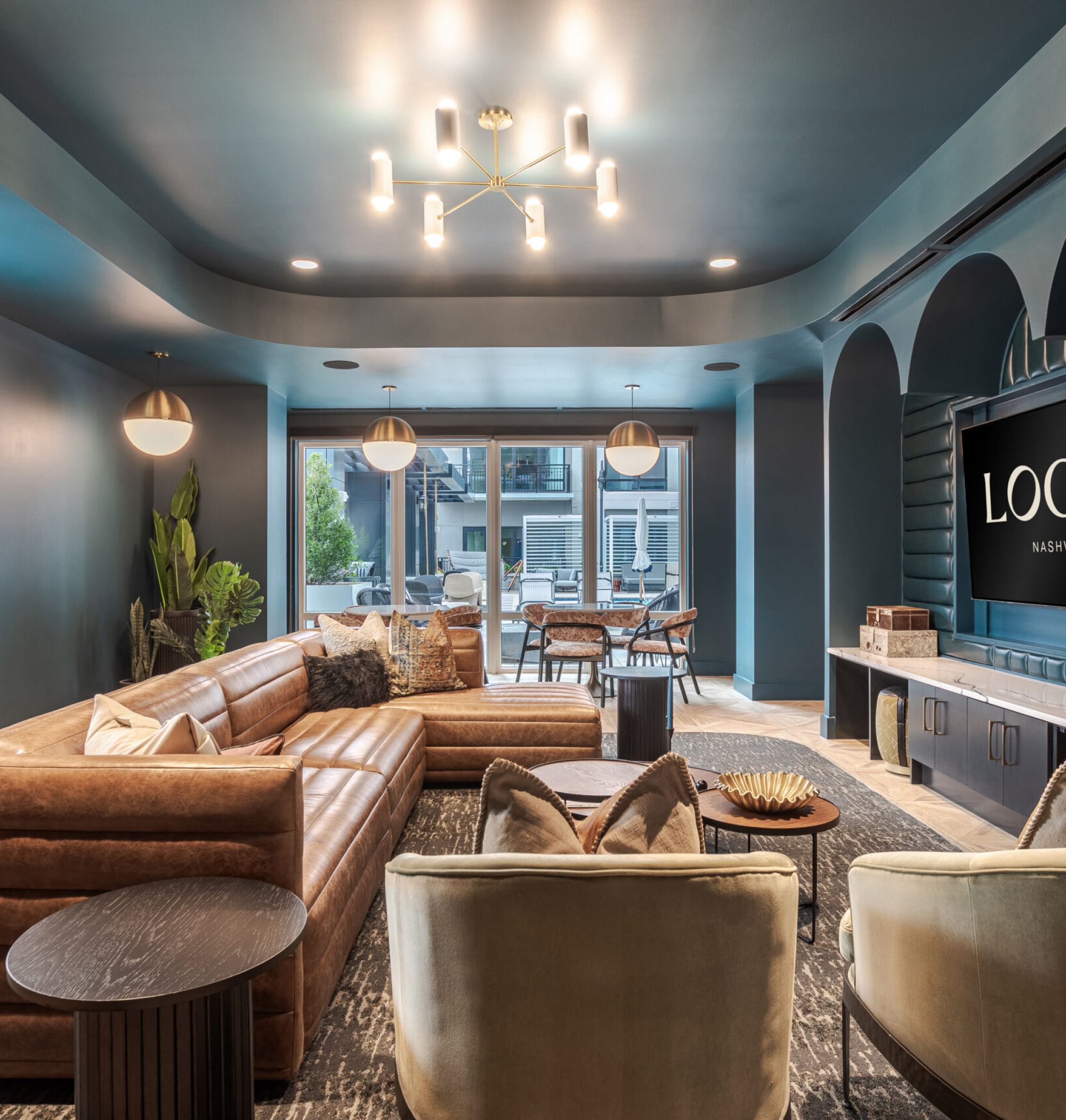 Local Nashville Apartments clubhouse media lounge with lounge seating, bar tables, and large tv's