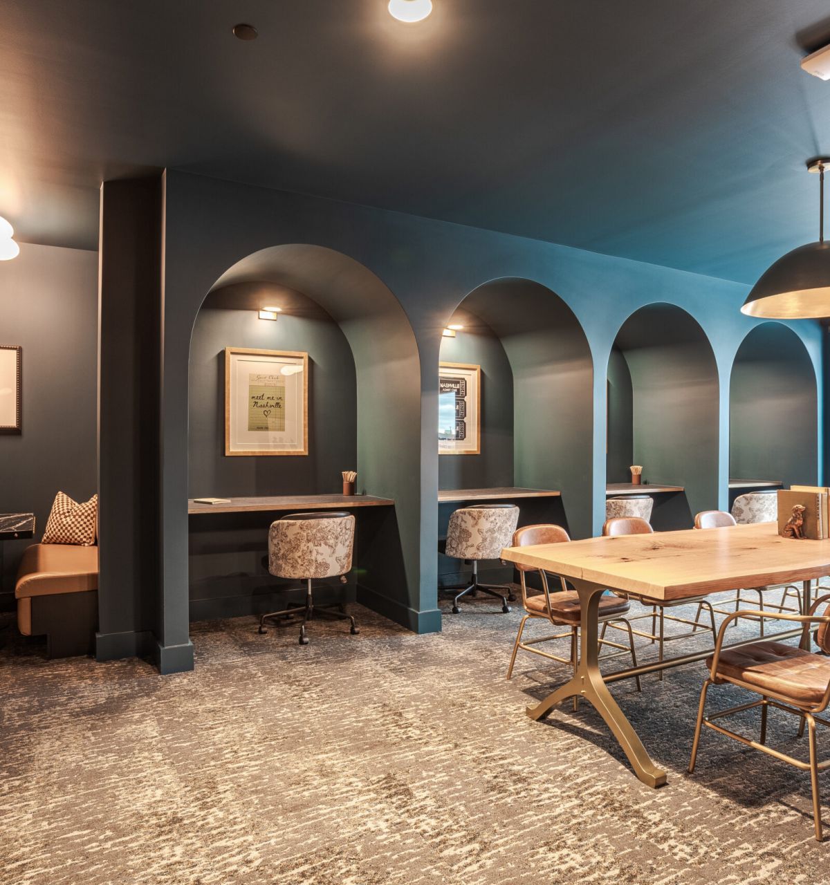 Elegant coworking space with arched alcoves, individual desks, cozy chairs, and a large table under soft lighting.