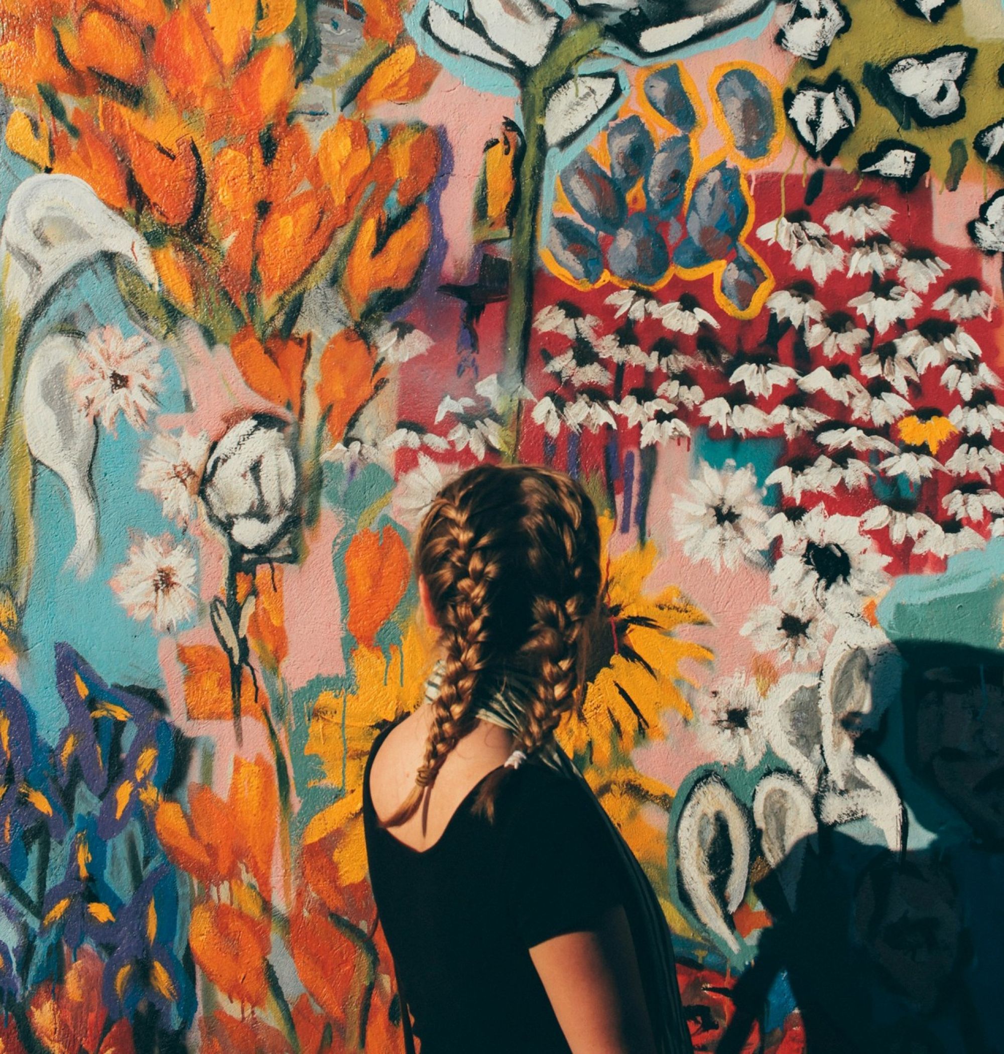 Young woman standing in front of a floral wall mural in Nashville, TN